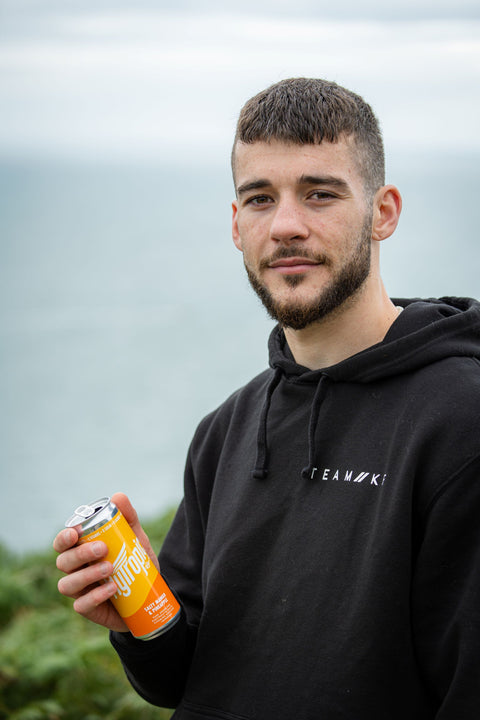 Man holding a can of drink outdoors with a blurred background