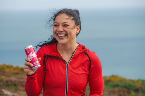 Woman in red jacket holding a can outdoors with a blurred background