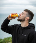 Man drinking from a can outdoors with a blurred background