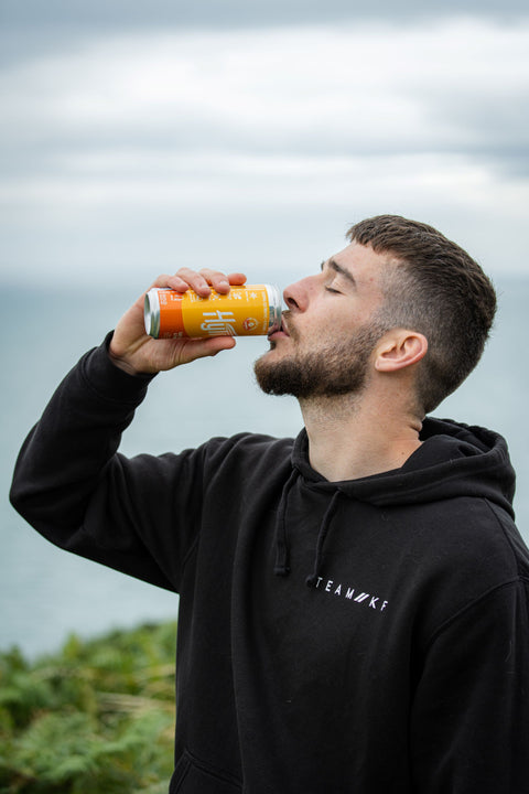 Man drinking from a can outdoors with a blurred background