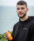Man holding a can of drink outdoors with a blurred background