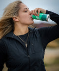 Woman drinking from a green can outdoors