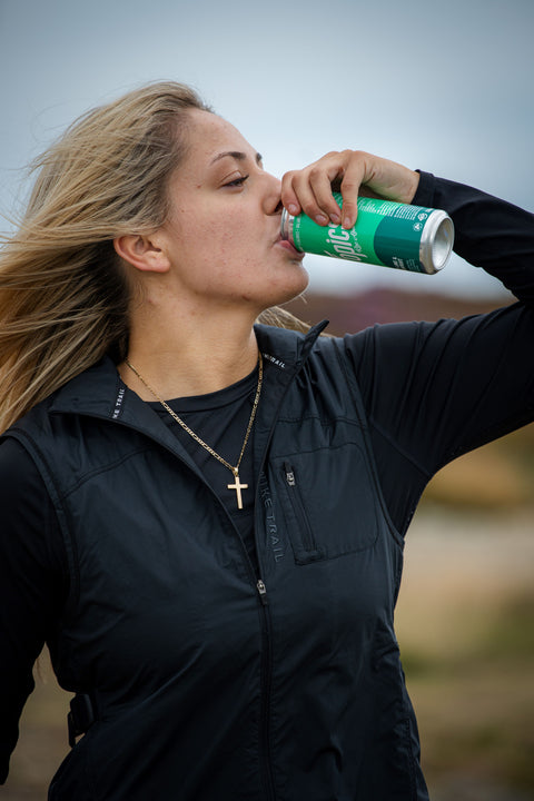 Woman drinking from a green can outdoors