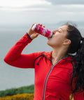 Woman in red jacket drinking from a Hytropics can outdoors