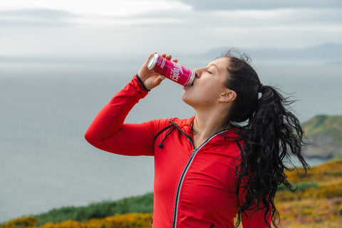 Woman in red jacket drinking from a Hytropics can outdoors