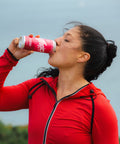 Woman in red jacket drinking from a red can of raspberry and elderflower outdoors