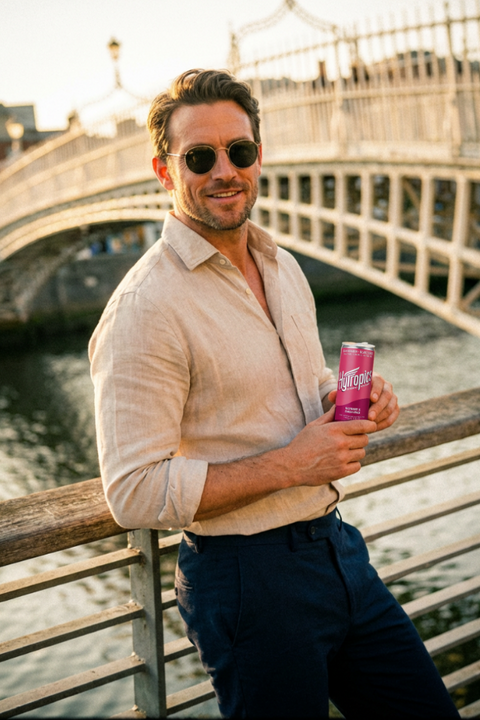Man holding a pink can by a bridge